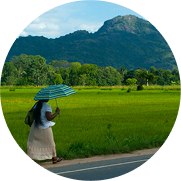 A woman stands at a work bench assembling a box of water bottles and other emergency supplies